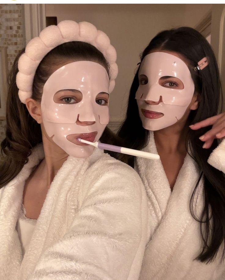 Two women wearing face masks and robes, one holding a toothbrush.