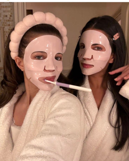 Two women wearing face masks and robes, one holding a toothbrush.